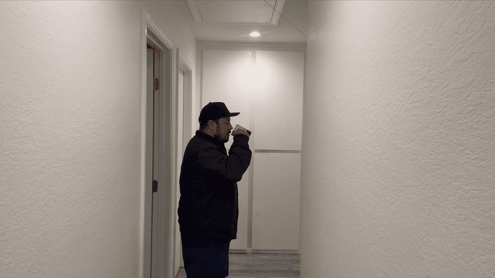 Reference video frame showing a man standing in a hallway drinking from a coffee mug, used as the motion blueprint